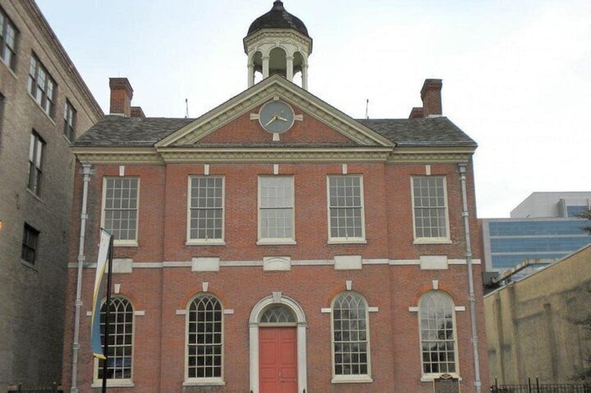 A red brick building with a clock tower, arched windows, and a red door. 5
