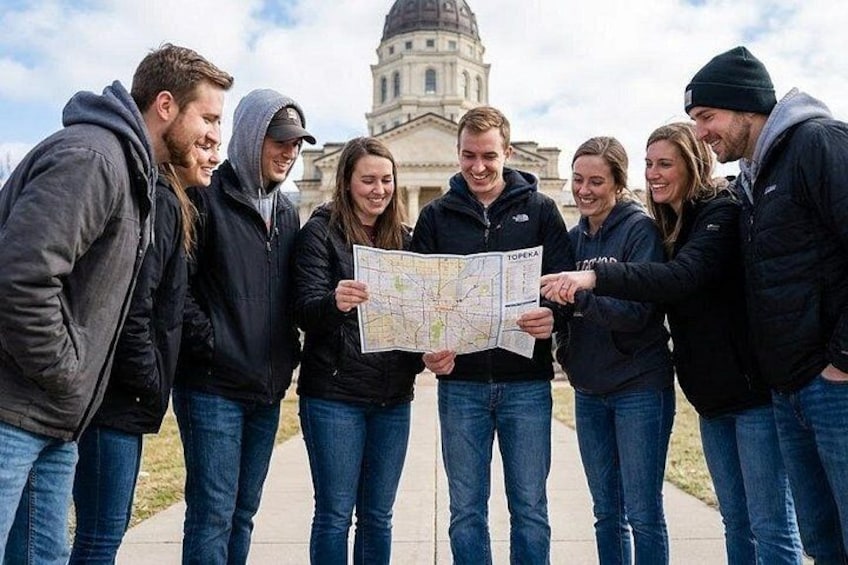 A group of people holding a map in front of a large building with a dome. 1
