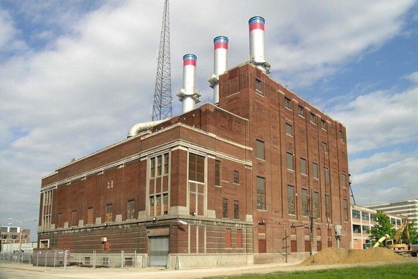 Un gran edificio industrial con tres chimeneas altas, una torre de metal y fachada de ladrillo. 5