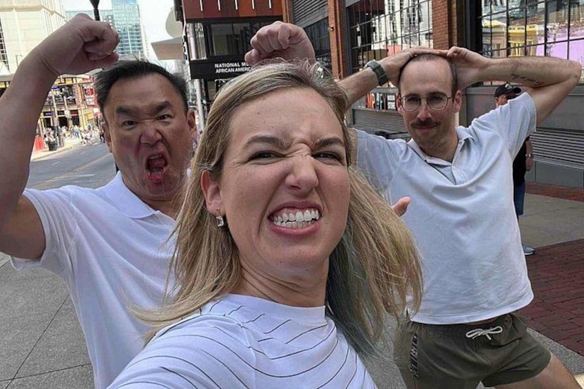 Tres personas tomándose un selfie en una calle de la ciudad, con edificios al fondo. 2