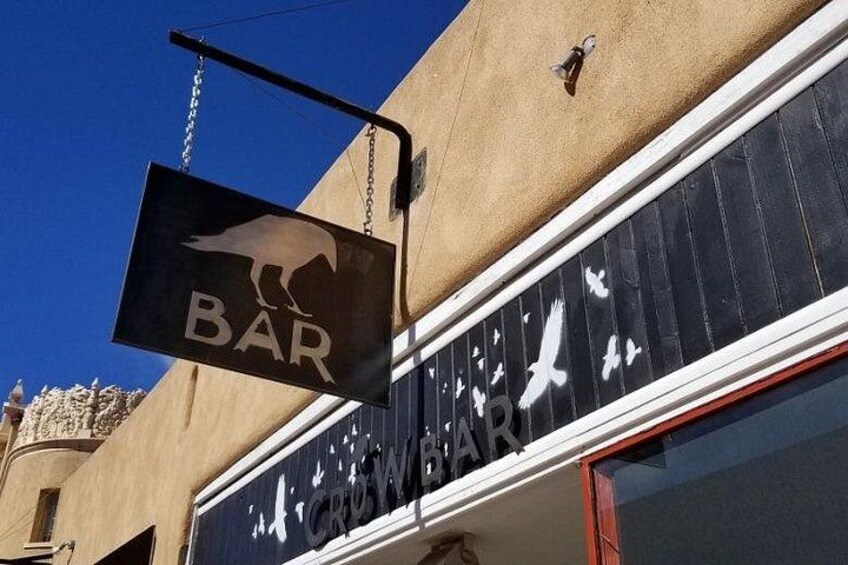 Un letrero de bar con la silueta de un ave y la palabra 'BAR' colgado de un edificio. 2
