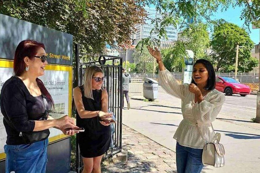 Three people standing on a sidewalk, one holding a smartphone. 2