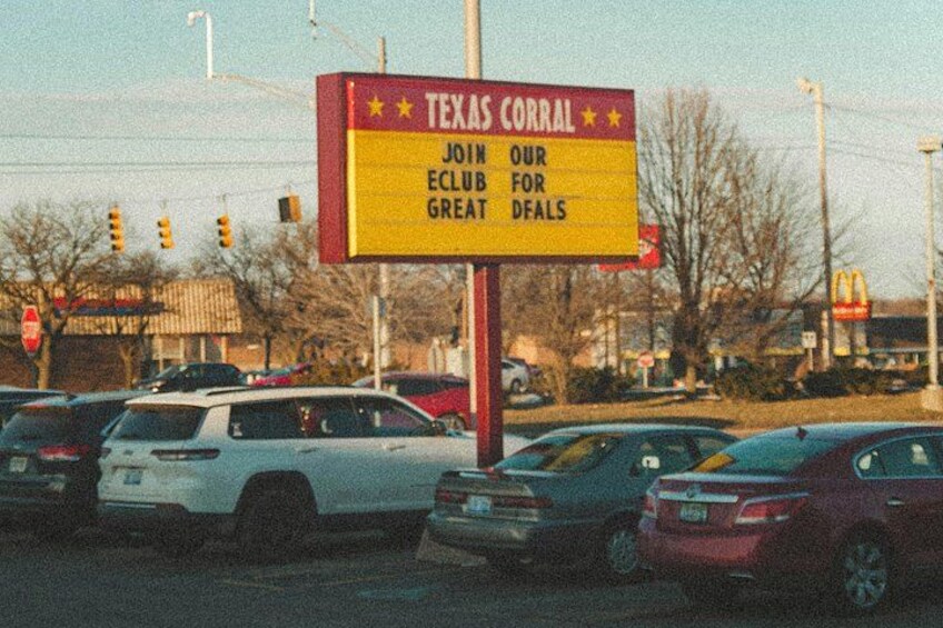 A Texas Corral sign with a yellow background and red border, advertising great deals. 4