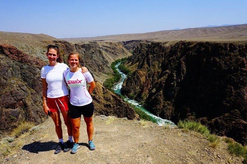 Two people standing on a rocky outcrop with a river flowing through a canyon in the background. 5