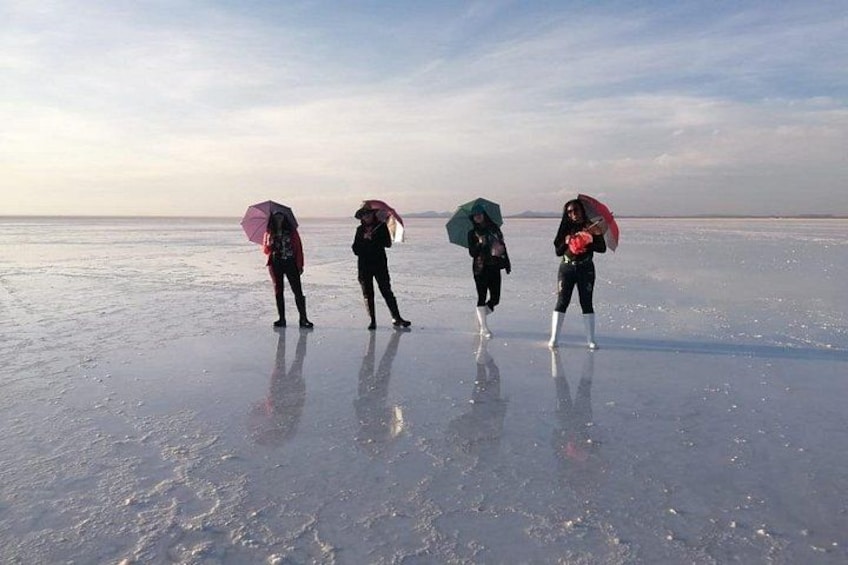 Four people walking on a frozen lake with umbrellas. 4