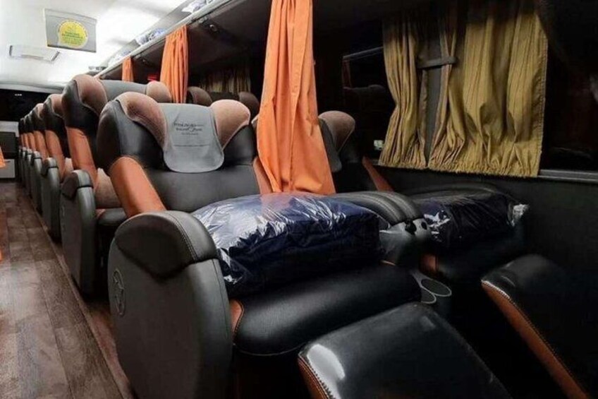 Une rangée de sièges inclinables avec des appuie-têtes orange et un coussin bleu sur l’un des sièges. 1