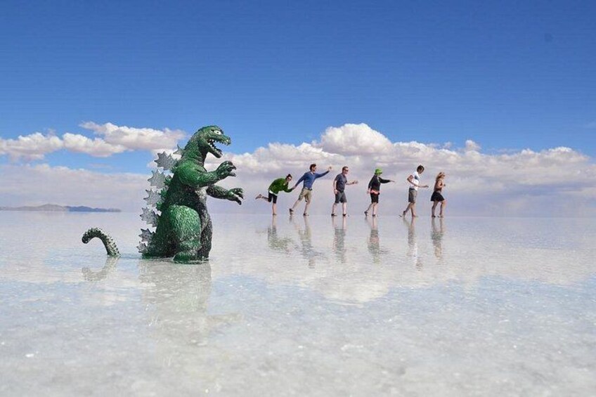 Un groupe de personnes joue avec un dinosaure en jouet dans une étendue d’eau importante, sous un ciel dégagé. 5