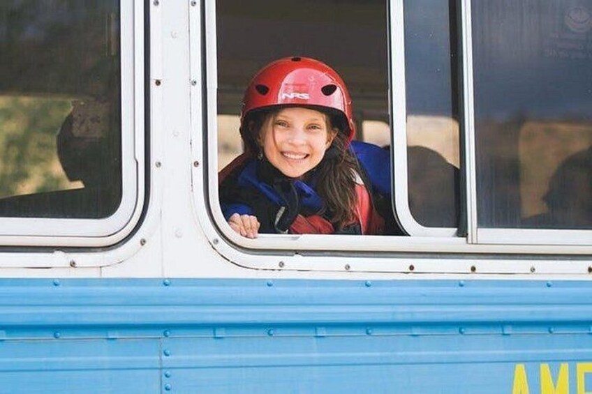 Una persona con un casco rojo y una chaqueta azul, mirando por la ventana de un autobús. 2