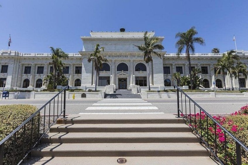 A grand building with a large staircase leading up to the entrance, palm trees, and a clear blue sky. 4