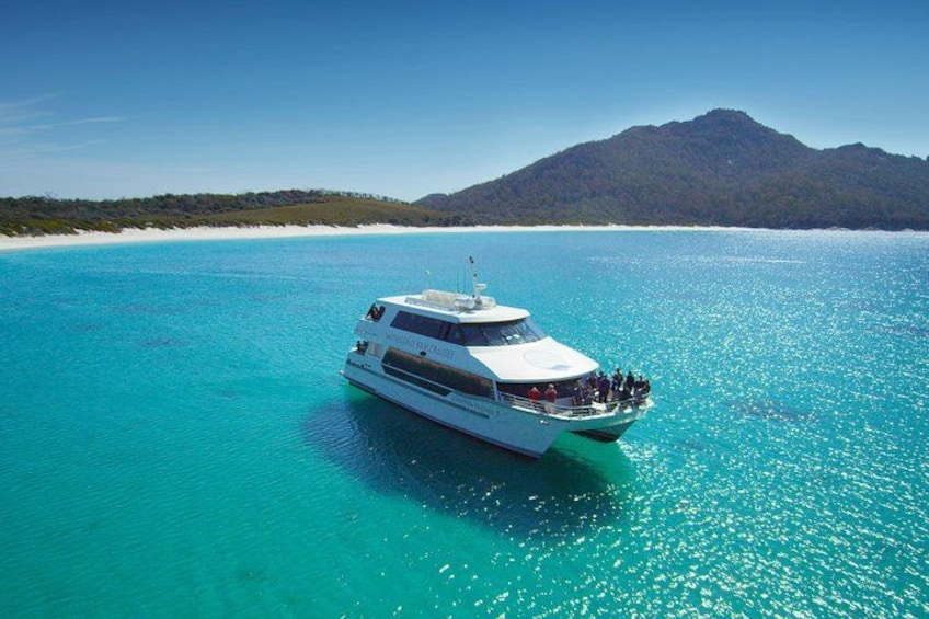 Un yate blanco sobre aguas turquesas, con un paisaje montañoso al fondo. 1