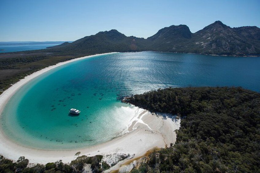 Un paisaje costero con un mar turquesa transparente, una playa de arena y un barco. 3