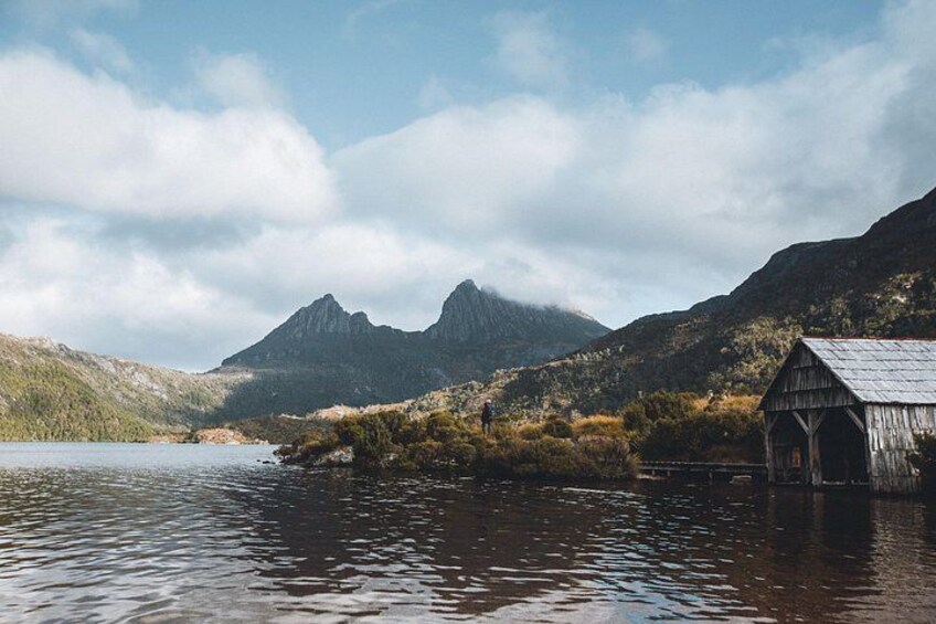 Una estructura de madera junto a un lago, con montañas al fondo. 4
