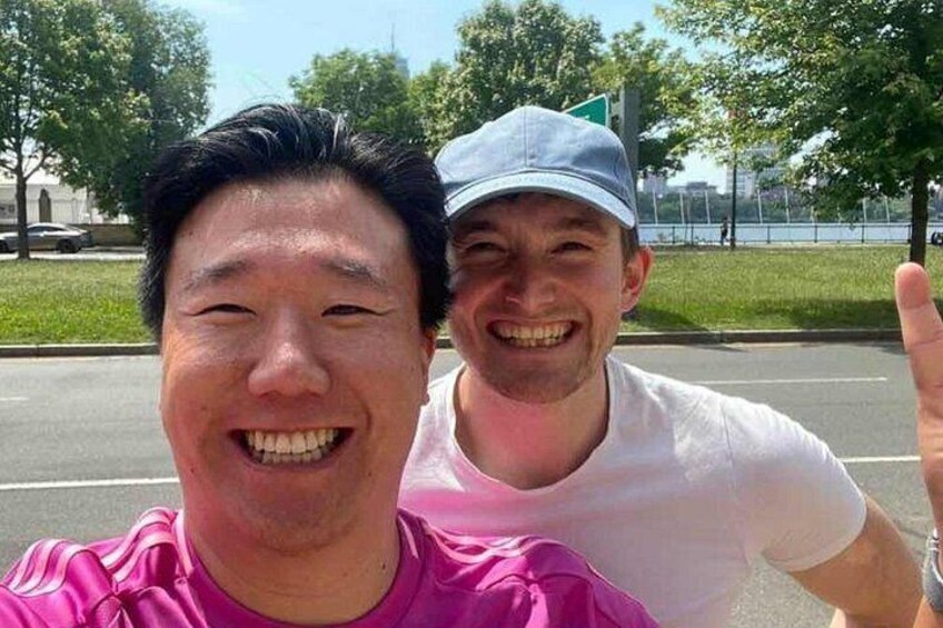 Dos personas tomándose un selfie con una carretera y follaje al fondo. 2