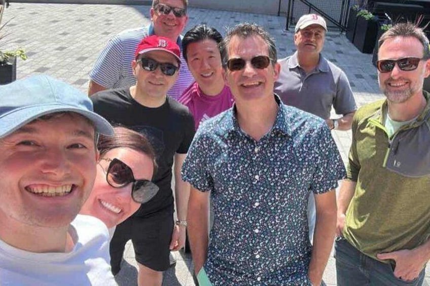 A group of people standing outdoors, some wearing hats and sunglasses. 2