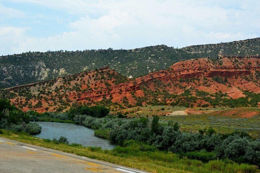 A river, green vegetation, and red rock formations. 4