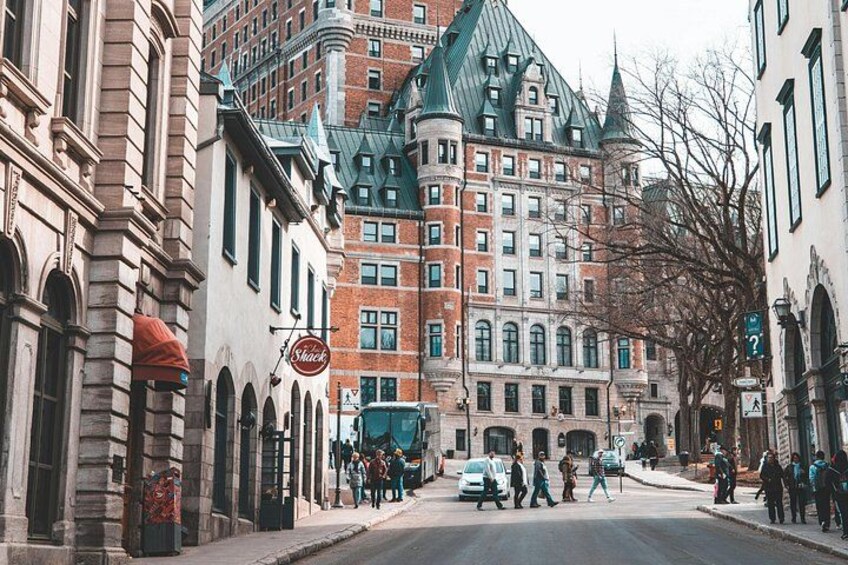 A street with historic buildings, a sign for a restaurant, and pedestrians. 1