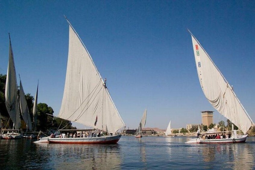 A fleet of sailboats with white sails on calm water, a bridge in the background, and a building with a red roof. 4