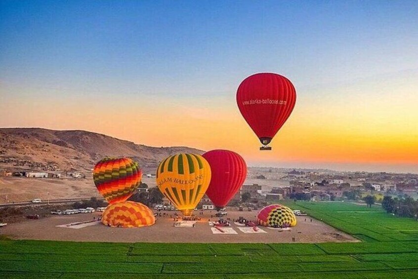 Hot air balloons over a field with a city in the background. 1