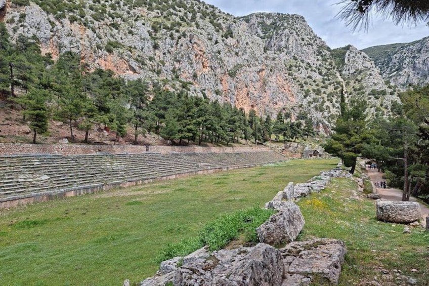 A grassy area with stone seating and a mountainous backdrop. 2