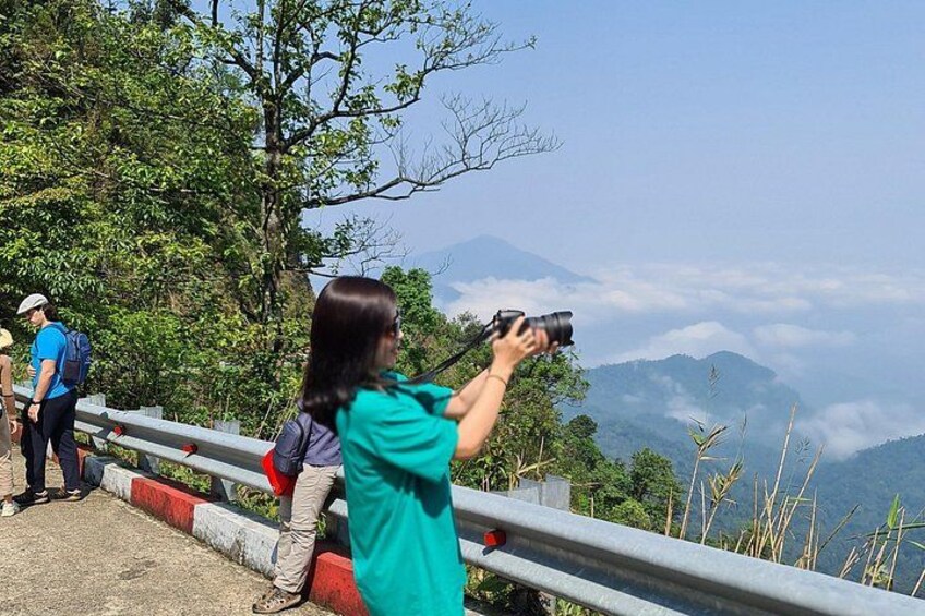 A person taking a photograph with a camera, overlooking a mountainous landscape with a clear sky. 1