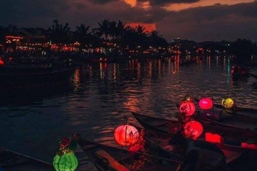 A nighttime scene with boats on a calm body of water, illuminated by colorful lanterns. 3