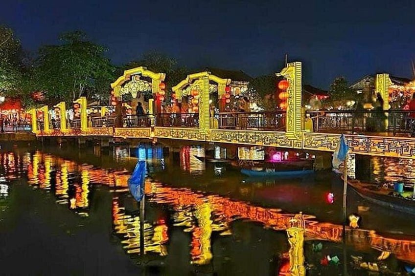 A brightly lit bridge with intricate designs, reflecting on the water below. 1