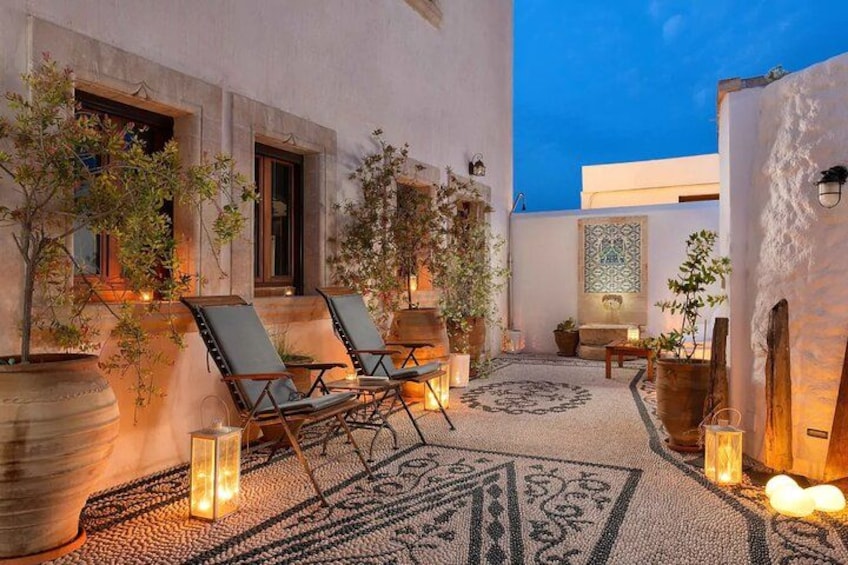 An outdoor seating area with lounge chairs, potted plants, and decorative lighting. 2