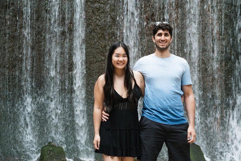 Een waterval met twee personen ervoor. 1