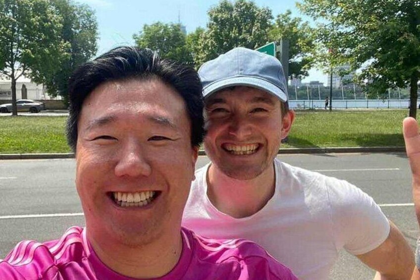 Dos personas tomándose un selfie al aire libre, con una carretera y follaje verde al fondo. 2