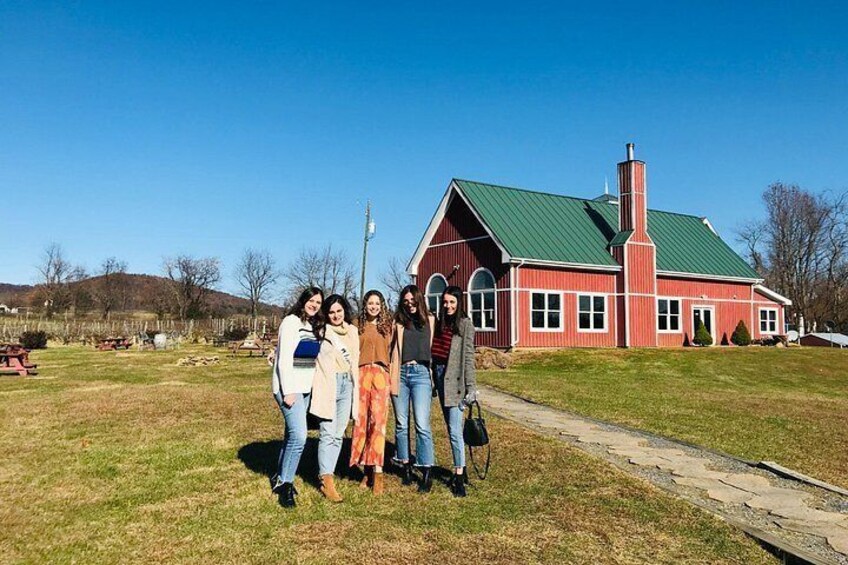 A group of people standing in front of a red building with a green roof. 5