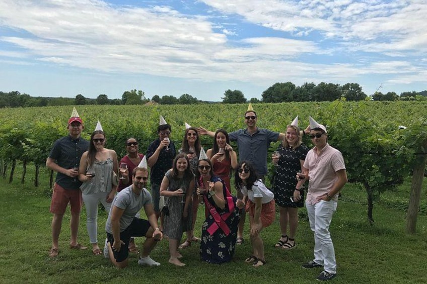 A group of people in a vineyard with rows of grapevines. 4