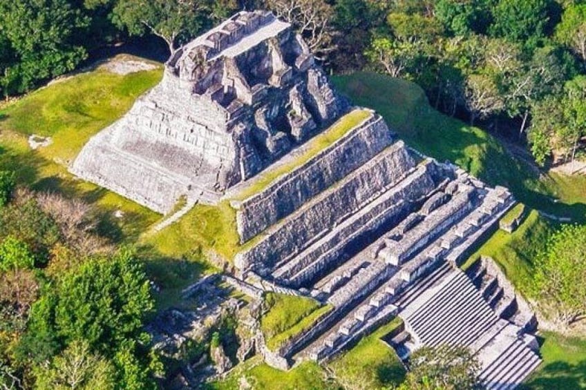 En pyramideformet struktur med flere niveauer og trapper, omgivet af grønt. 5