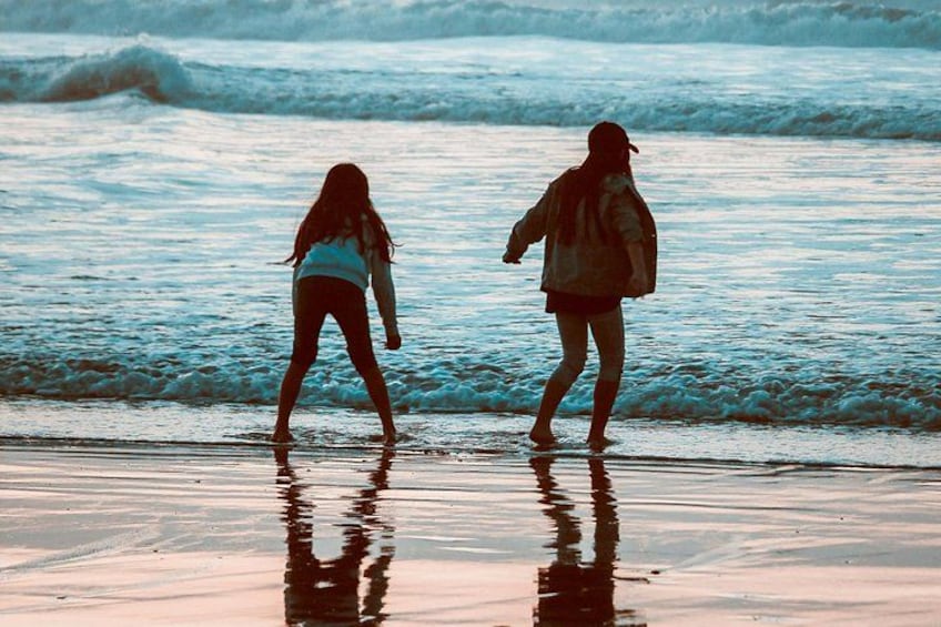 Two people walking along a beach with waves in the background. 2