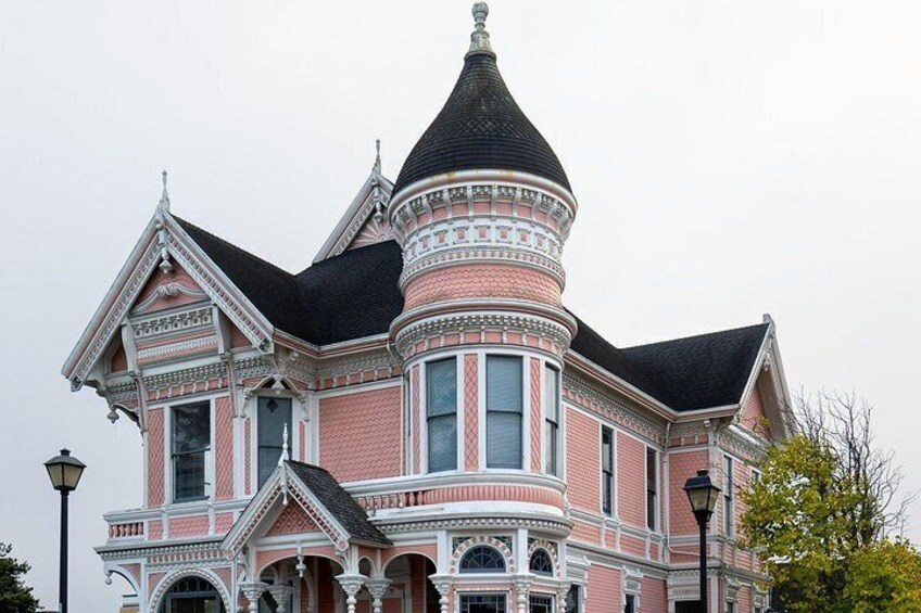 Un'ampia casa in stile vittoriano, rosa e bianca, con una caratteristica torretta e decorazioni elaborate. 4