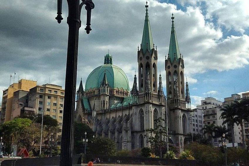 Una cattedrale storica con due alti pinnacoli e una grande cupola, circondata da edifici urbani. 4