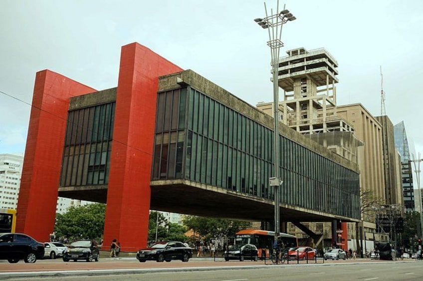 Un edificio moderno con ampie colonne rosse e una galleria coperta. 3