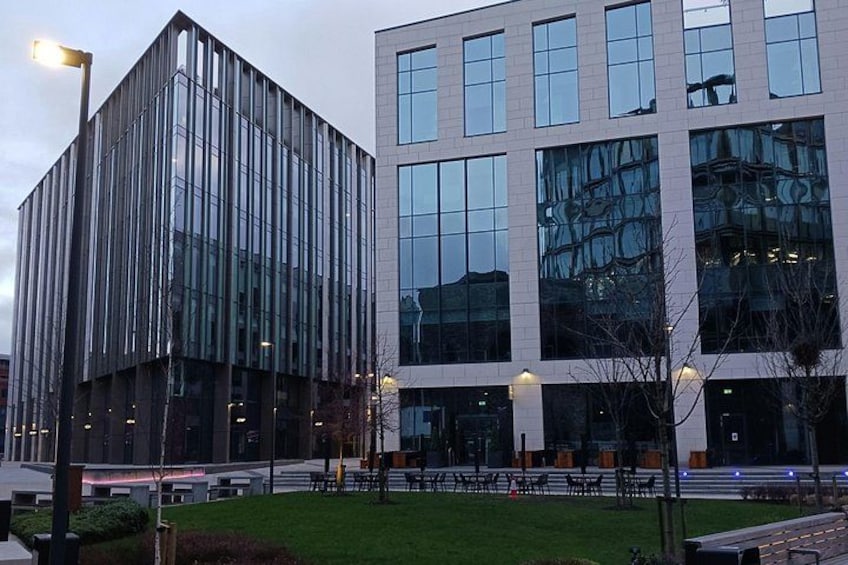 A modern building with reflective glass windows and a flat roof, surrounded by a well-maintained grassy area and a few trees. 1