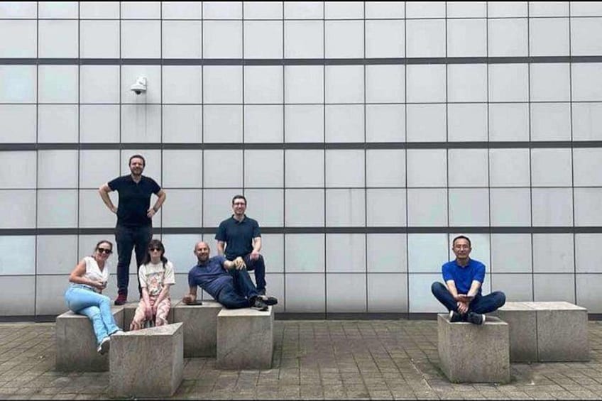 A group of people sitting on concrete blocks against a tiled wall. 3