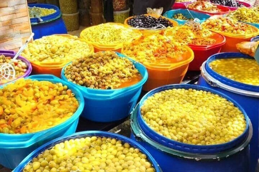 A variety of food items displayed in large blue and orange containers at a market. 3