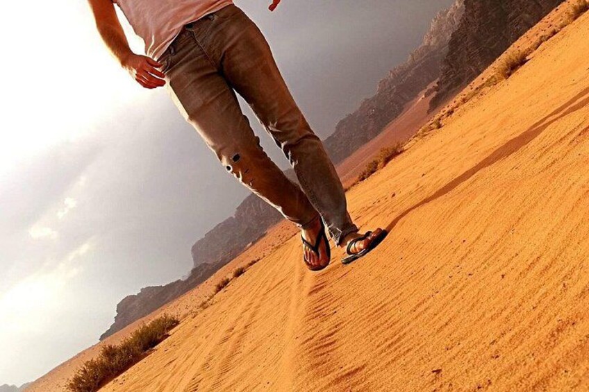 A person walking on a sandy dune with a mountainous landscape in the background. 3