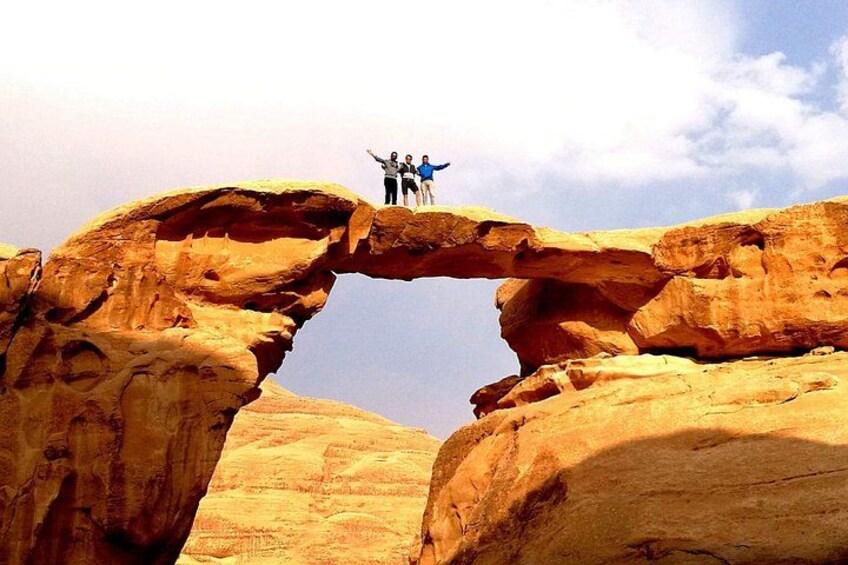A natural rock arch formation with two people standing on top. 2