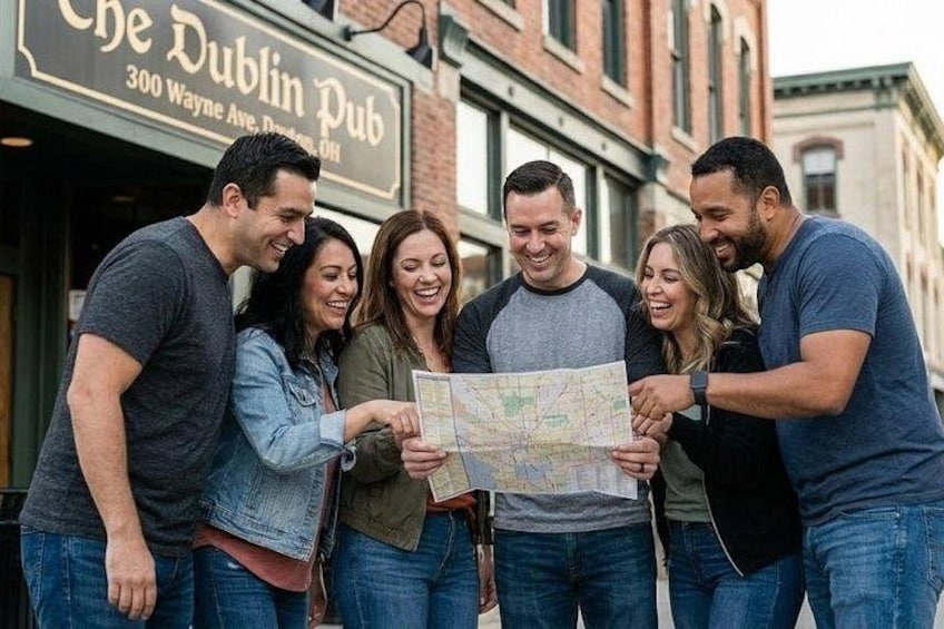 A group of people standing outside a pub, looking at a map. 1