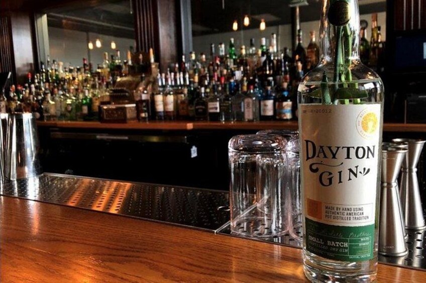 A bottle of Dayton Gin on a bar counter with a glass and a metal shaker behind it. 4
