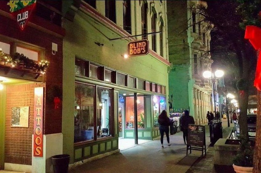 A nighttime street scene with storefronts, including a visible sign for 'BLIND BOB'S.' 3