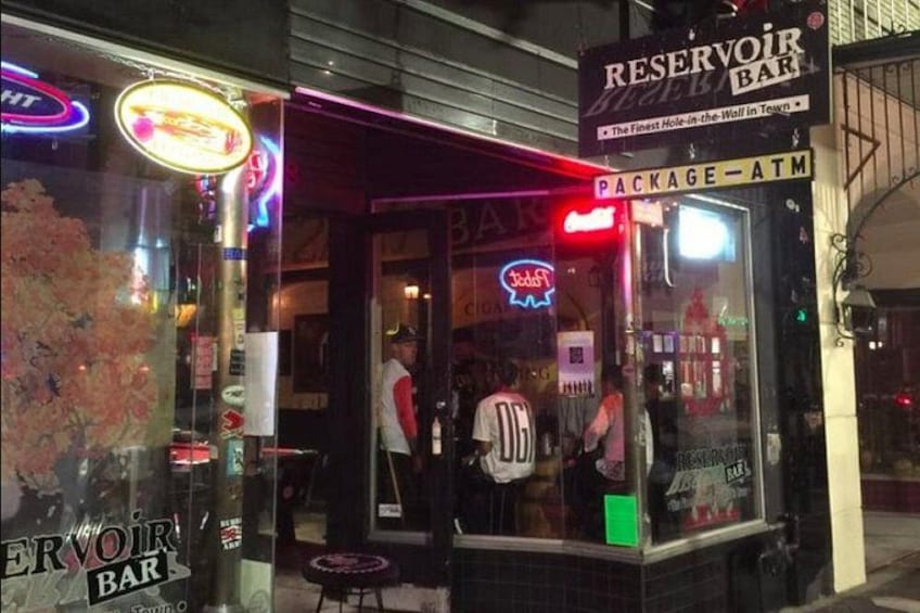 Un bar avec des enseignes au néon, un distributeur automatique de billets et une personne portant un maillot aux couleurs de « DC ». 3