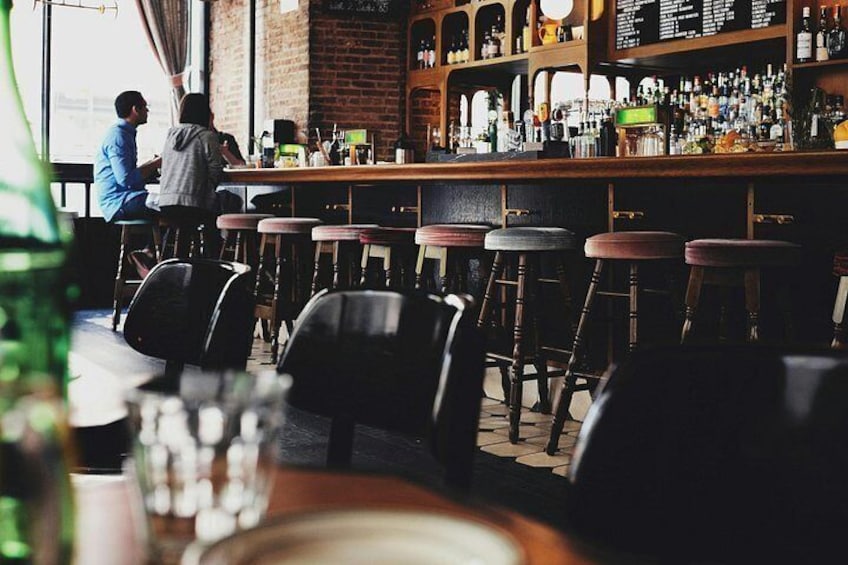 A bar with stools, a counter with bottles, and a brick wall. 2