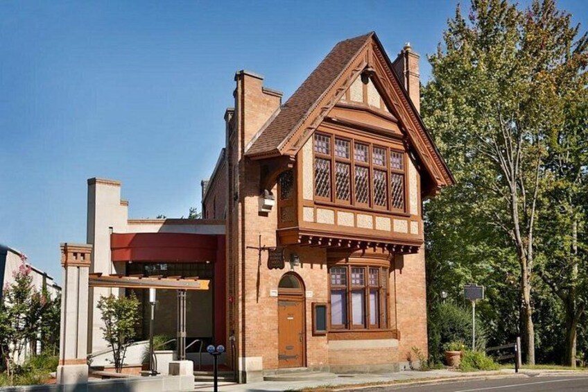 A two-story brick building with a gabled roof and large windows. 3