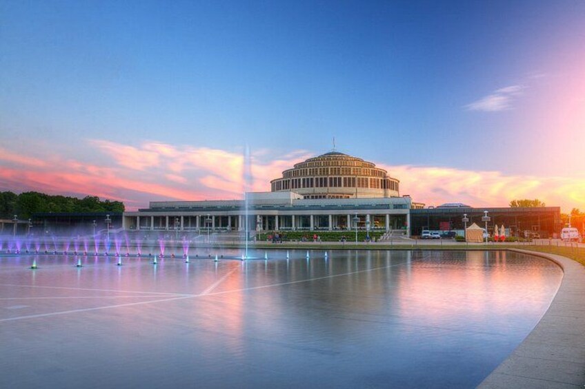 A large circular building with a fountain in front. 3