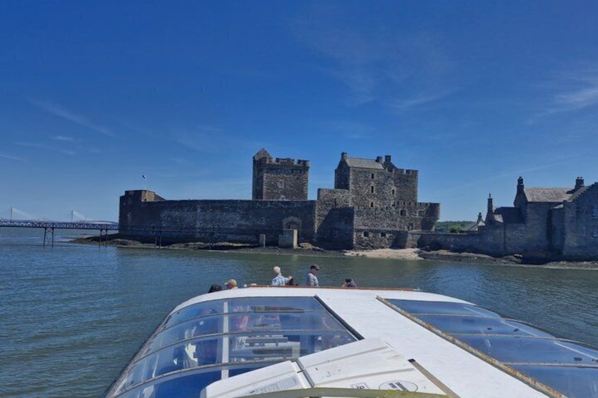 Una barca che offre una vista chiara di un castello storico in pietra affacciato sull'acqua. 1