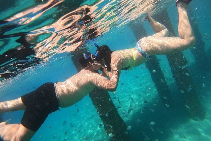 Two people swimming underwater near a structure. 4